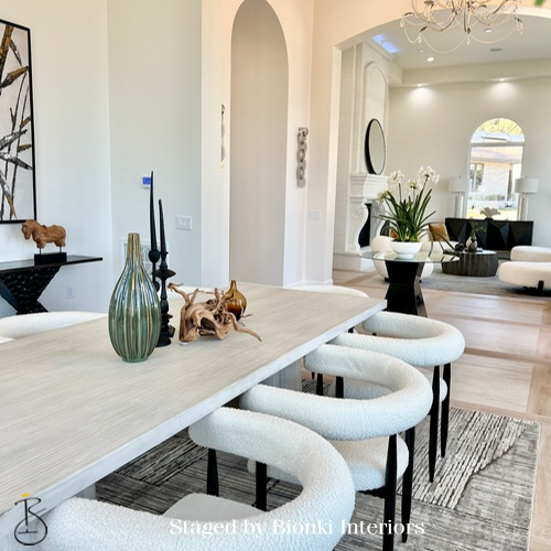 Luxury open-concept dining and living area staging featuring curved seating and refined accessories designed to emphasize architectural flow. Staged by Bionki Interiors. Luxury open-concept dining and living area staging featuring curved seating and refined accessories designed to emphasize architectural flow. Staged by Bionki Interiors.