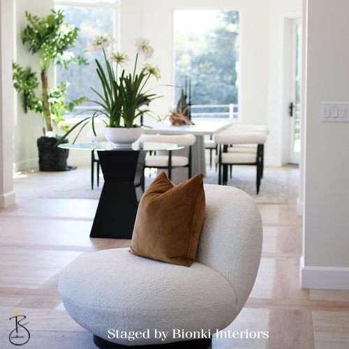 Luxury open-concept staging featuring sculptural seating and organic textures designed to highlight flow between living and dining areas. Staged by Bionki Interiors. Luxury open-concept staging featuring sculptural seating and organic textures designed to highlight flow between living and dining areas. Staged by Bionki Interiors.