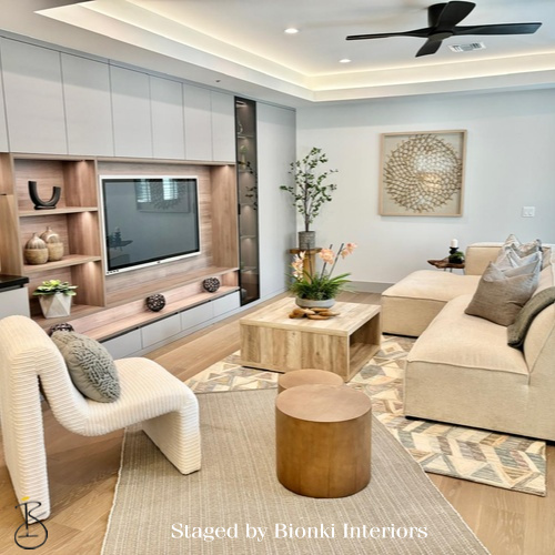 Luxury vacant home staging for a modern living room featuring a built-in media wall, warm wood tones, and layered textures. Staged by Bionki Interiors. Luxury vacant home staging for a modern living room featuring a built-in media wall, warm wood tones, and layered textures. Staged by Bionki Interiors.