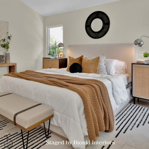 Luxury primary bedroom staging featuring layered neutral bedding and warm textile accents designed to create a calm and inviting retreat. Staged by Bionki Interiors. Luxury primary bedroom staging featuring layered neutral bedding and warm textile accents designed to create a calm and inviting retreat. Staged by Bionki Interiors.
