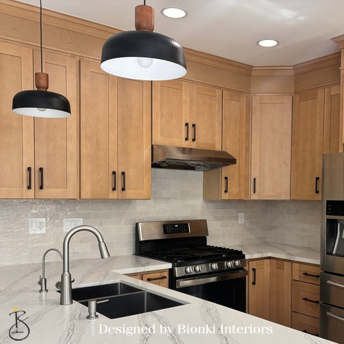 Custom kitchen design featuring warm wood cabinetry and modern pendant lighting. Designed by Bionki Interiors.