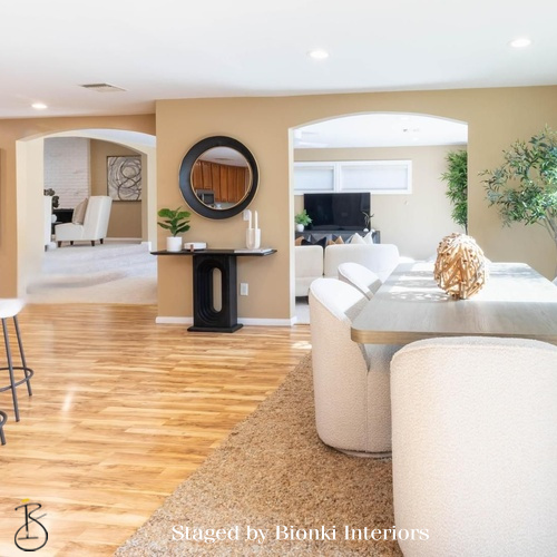 Luxury open-concept home staging featuring cohesive flow between living and dining areas with warm wood flooring. Staged by Bionki Interiors. Luxury open-concept home staging featuring cohesive flow between living and dining areas with warm wood flooring. Staged by Bionki Interiors.