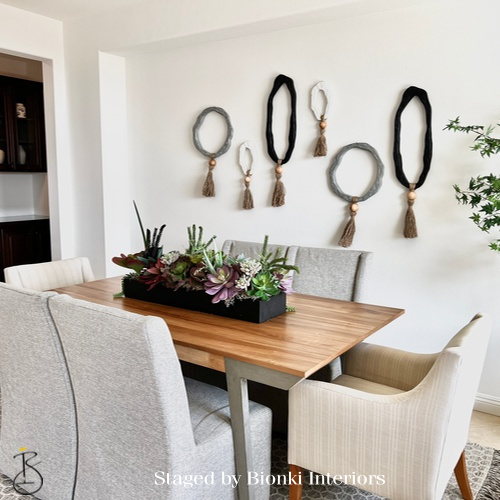 Luxury dining room staging featuring a natural wood table, upholstered seating, and curated wall accents designed for everyday living and entertaining. Staged by Bionki Interiors. Luxury dining room staging featuring a natural wood table, upholstered seating, and curated wall accents designed for everyday living and entertaining. Staged by Bionki Interiors.