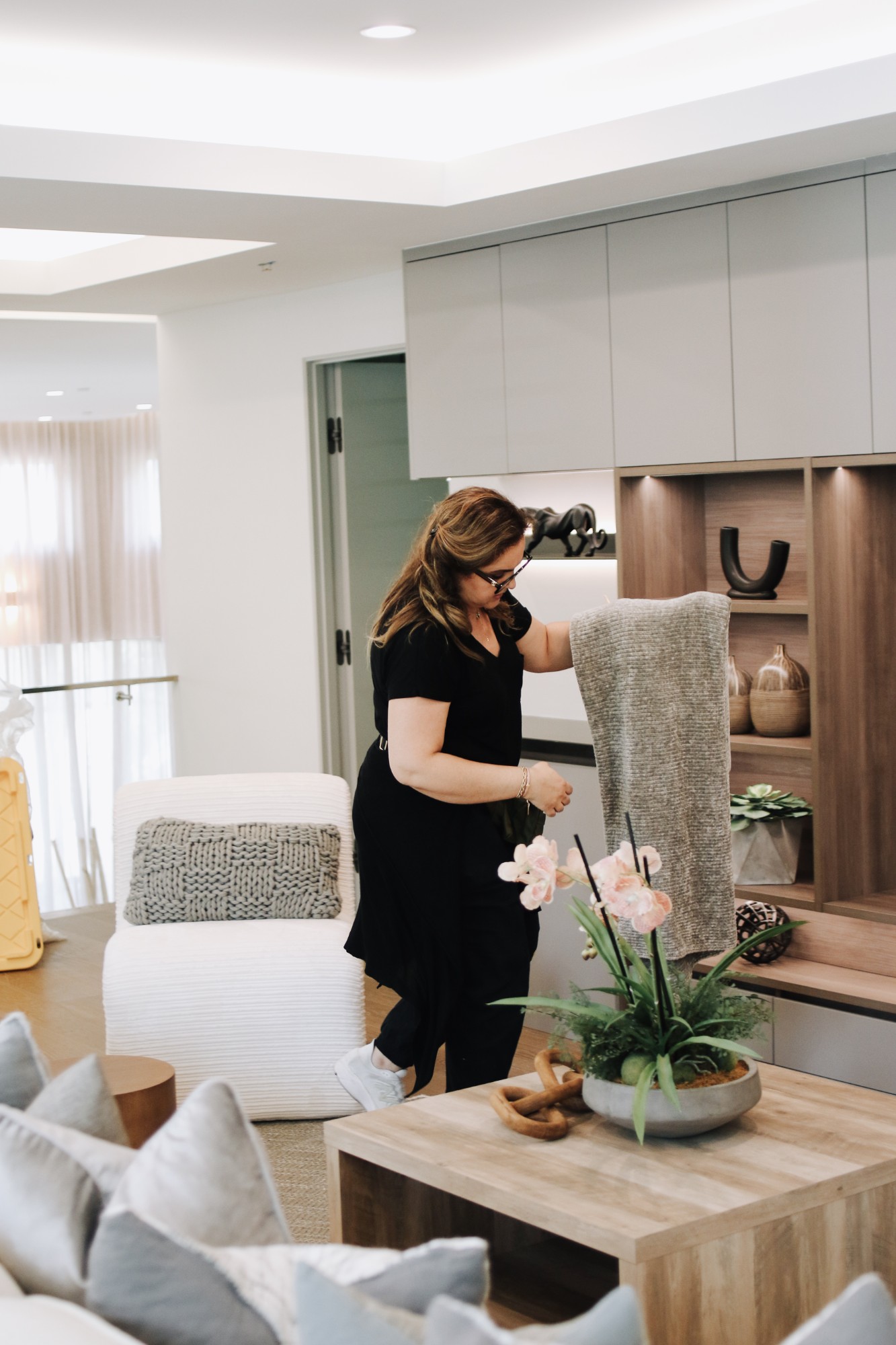 Pantea Bionki styling a living room with built-in shelving, an accent chair, and a coffee table with orchids